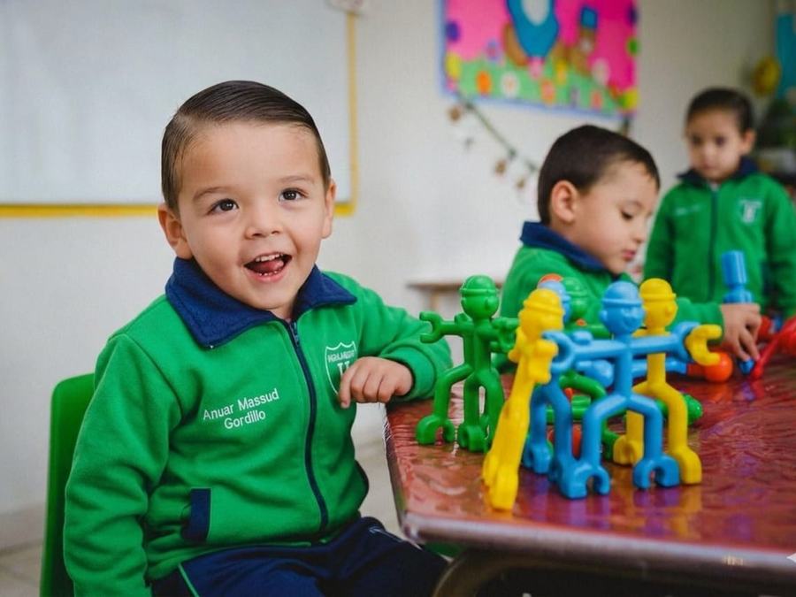 Niño de maternal sonriendo mientras juega con material de construcción
