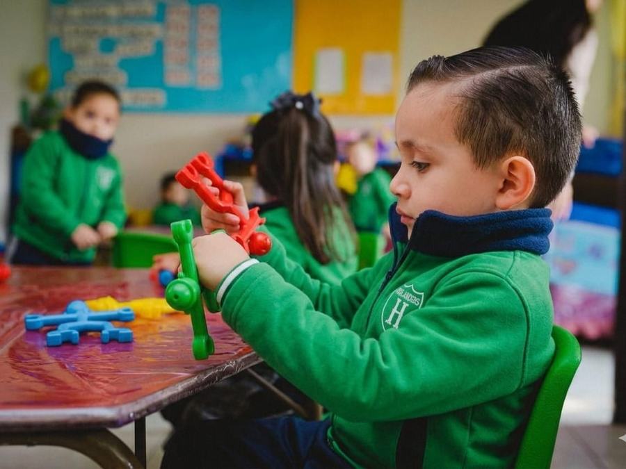 Niño de preescolar concentrado armando una figura en el salón