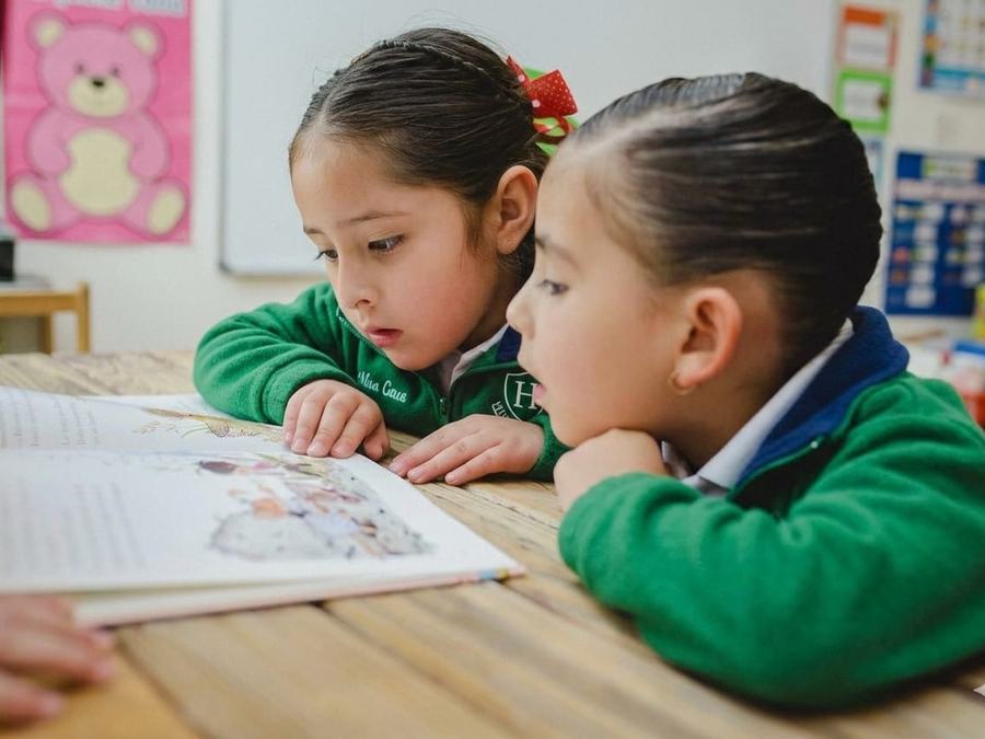 Dos alumnas de primaria leyendo juntas un libro ilustrado
